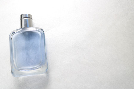 Blue rectangular beautiful glass transparent shiny fashionable glamorous bottle of cologne, perfume with silvery bezel and place for sample text on a gray light backgroundの写真素材