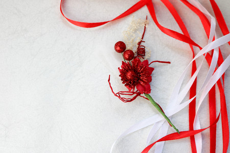 Texture red shiny artificial decorative flower decorated with balls with red and white beautiful festive ribbons made of artificial fabric on a light gray background. The background.の写真素材