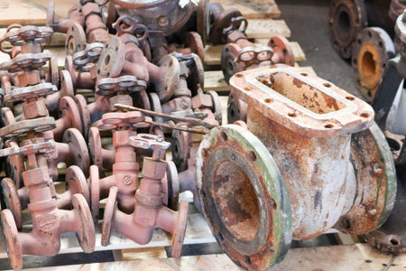 Large rusty old metal gate valve, pipe fittings, against the background of small valves, pipeline...