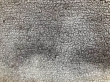 Texture of a black gray old dilapidated concrete wall with pieces of old shabby exfoliated paint with cracks, veins backgroundの写真素材