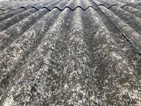 Texture of old dilapidated bulk gray slate, sloping roof of asbestos located vertically covered with green moss backgroundの写真素材