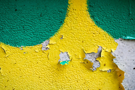 Texture of a two-color yellow and green old shabby concrete wall with bulbous peeling varicoloured paint, pits and patterns, background.の写真素材