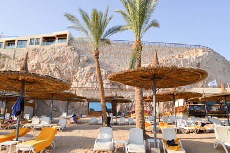 A beautiful sandy beach with schlzols, sun-shaped umbrellas in the form of straw hats on the...