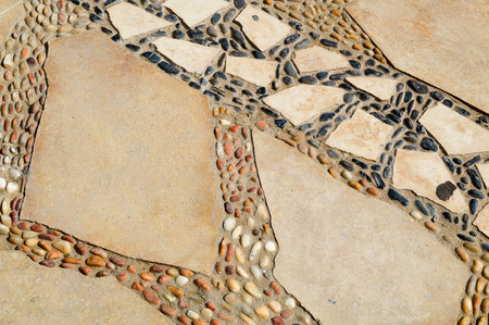 The texture of the road is laid out of small round white brown and black stones and granite fragments from cobblestones with patterns.の写真素材