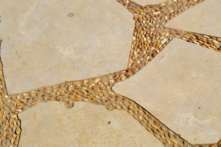 The texture of the road is laid out of small round white white granite stones and granite fragments...