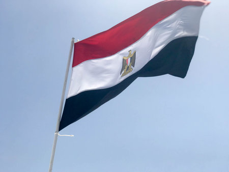 A large black and white Egyptian flag flying in the wind against the blue sky.