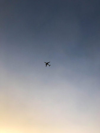 A large passenger aircraft with wings flies, soars high in the blue sky in the evening at sunset.