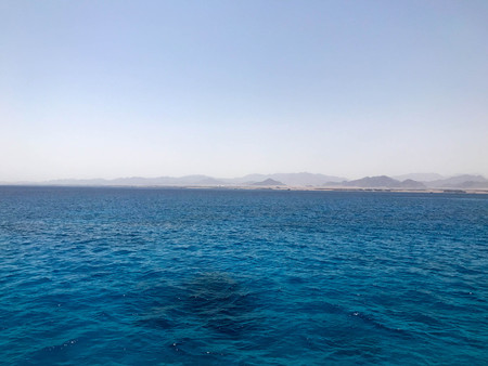 Landscape of transparent blue periling sea salt water, sea, ocean with waves, ripples under the scorching sun against the backdrop of distant mountains.の写真素材