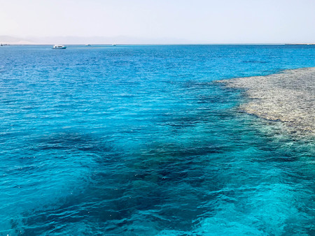 Landscape of transparent blue periling sea salt water, sea, ocean with waves with a bottom of beautiful coral reefs, stones against the backdrop of distant mountains.の写真素材