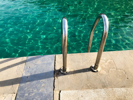 Metal chrome iron shiny curved stainless steel handrails, stairs, descent into the pool, the sea,...