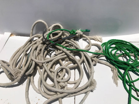 White and green strong fabric ship ropes, ropes lie in a pile on a ship, boat on a white background.