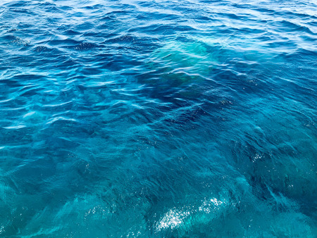 The texture of a beautiful scenic azure blue sea, ocean salty calm wet water with waves, ripples on the water. The background.の写真素材