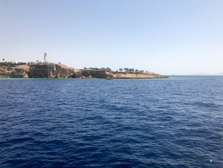 Seascape of the distant beautiful tropical brown stone mountains and various buildings on the shore...