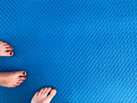 Texture with male and female feet, legs with a beautiful red manicure on the fingers stand on a blue...