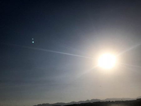 A beautiful view of the big bright hot hot yellow sun against the background of distant mountains in a tropical seaside resort. The background.の写真素材
