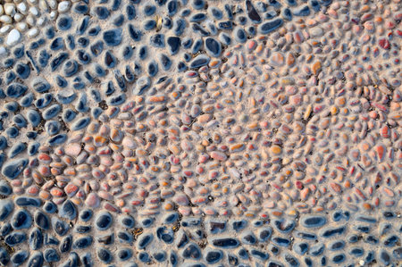 The texture of the stone wall, the road from small round and oval stones with abstract lines laid...