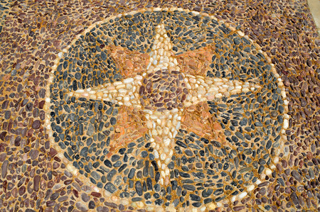 The texture of the stone wall, the road from small round and oval stones with abstracted lines of star patterns sandy seams of the natural old yellow black brown. The background.の写真素材