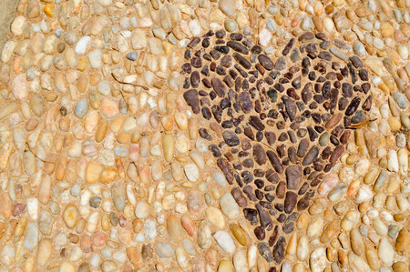 The texture of the stone wall, the road from small round and oval stones with abstracted lines of heart patterns sandy seams of natural old yellow black brown. The background.の写真素材