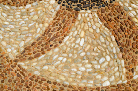 The texture of the stone wall, the road from small round and oval stones with abstract lines laid out patterns of sandy seams of natural old yellow black brown. The background.の写真素材