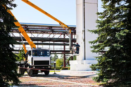 Repair columns on a special technique. Workers on the crane repair a large white column. Cosmetic...