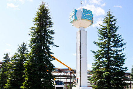 Repair of the tower clock. Workers on the crane repair clock-column, clock on the tower, paint,...