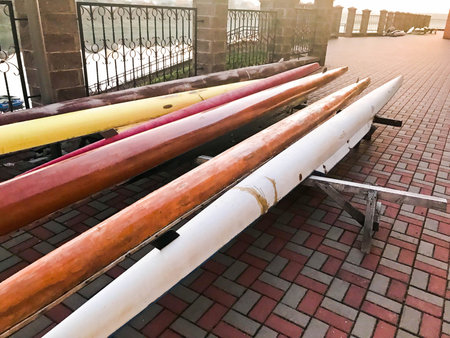 Large team long multi-seater paddle boats for water sports on the beach on stone tiles.