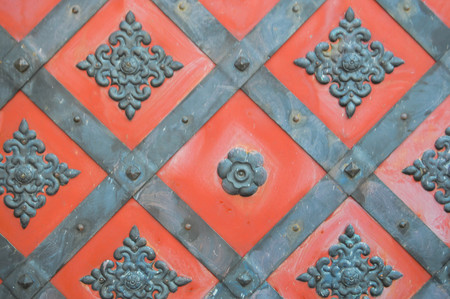 Texture of an old ancient medieval red antique sturdy iron metal door with rivets and nails patterns. The background.の写真素材