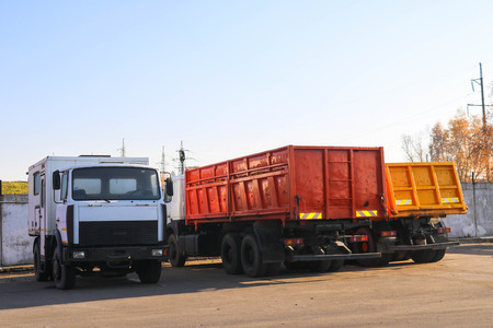 Large heavy cargo trucks with cabs and trailers, dump trucks stand in a row in the parking lot ready for delivery.の写真素材
