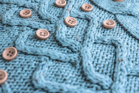 Beautiful texture of a soft warm natural sweater with a knitted pattern of yarn and red small round...