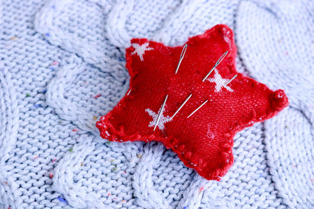 Beautiful texture of a soft warm natural sweater, a fabric with a knitted pattern and a needle pad for sewing. Flat lay. The background.の写真素材