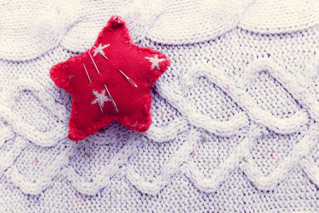 Beautiful texture of a soft warm natural sweater, a fabric with a knitted pattern and a needle pad...