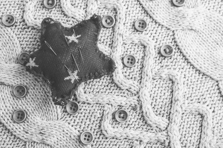 Beautiful texture of a soft warm natural sweater, knitted fabrics and red small round buttons for sewing and a needle pad. Flat lay. The background.の写真素材