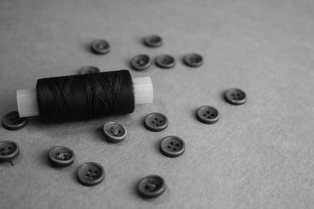 Beautiful texture with many round black and white buttons for sewing, needlework and a coil of thread. Copy space. Flat lay. the background.の写真素材