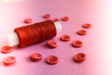 Beautiful texture with many round pink buttons for sewing, needlework and a coil of thread. Copy space. Flat lay. Pink, purple background.の写真素材