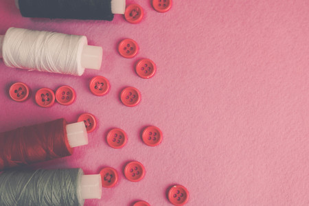 Beautiful texture with lots of round red buttons for sewing, needlework and skeins of spools of thread. Copy space. Flat lay. Pink, purple background.の写真素材