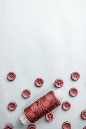 Beautiful texture with lots of round red buttons for sewing, needlework and a coil of thread. Copy space. Flat lay. Blue background.の写真素材