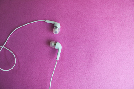 Beautiful modern digital plastic vacuum white headphones with wires for listening to music on a purple pink background. Copy space.の写真素材