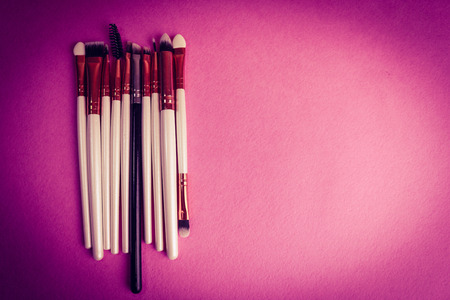 A set of beautiful different soft brushes for make-up from natural nap for beauty targeting and applying a tonal foundation in a stand and copy space on a pink, purple background.の写真素材