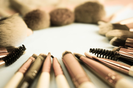 A frame from a set of beautiful different soft makeup brushes from natural lint for targeting beauty and applying a tonal foundation in a stand and copy space on a blue background.の写真素材