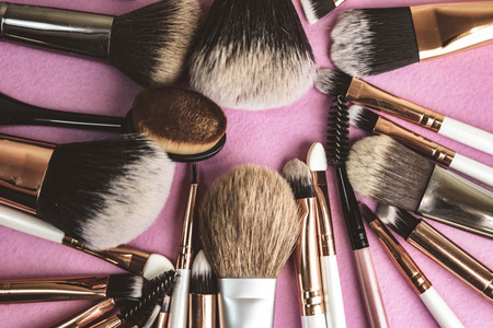 A set of beautiful different soft brushes for make-up from natural nap for beauty targeting and applying a tonal foundation in a stand and copy space on a pink, purple background.の写真素材