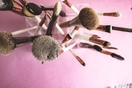 A set of beautiful different soft brushes for make-up from natural nap for beauty targeting and applying a tonal foundation in a stand and copy space on a pink, purple background.の写真素材