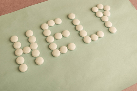 Beautiful inscription help made from white round smooth medical pills, vitamins, antibiotics and copy space on a bright blue background. Flat lay.の写真素材