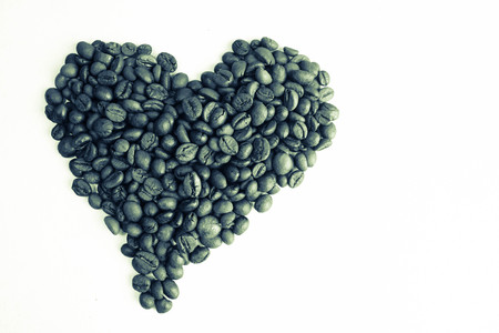 Beautiful texture in the shape of a heart from freshly roasted selected delicious saturated brown natural fragrant Arabica and Robusta coffee beans. Copy space, flat lay, isolated white background.の写真素材