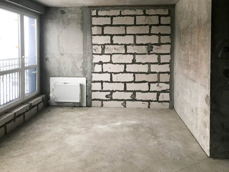 The apartment in the new building with a free layout without repair and decoration with bare walls and a large panoramic French window on the whole wall. Concept: repair, housewarming, building.の写真素材