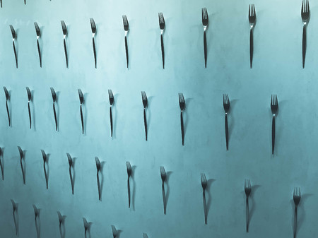 Pattern of a variety of metal forks, cutlery on the wall on a blue background. Texture.の写真素材