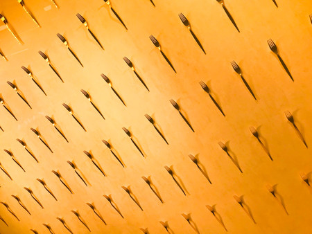 The pattern of a variety of metal forks, cutlery on the wall on a yellow background. Texture.の写真素材