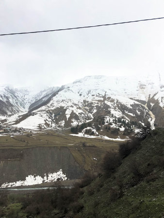 Beautiful mountain cold winter resort landscapes with high mountain peaks mist and snow covered...