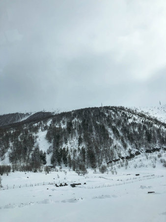 Beautiful mountain cold winter resort landscapes with high mountain peaks mist and snow covered...