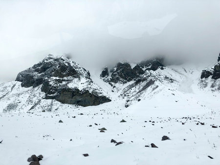 Beautiful mountain cold winter resort landscapes with high mountain peaks mist and snow covered...