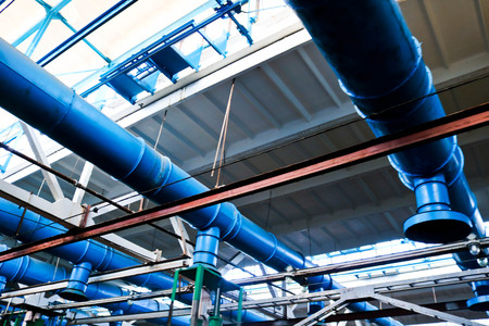 The ceiling in the workshop at the industrial chemical petrochemical machine-building refinery with blue metal iron large pipes of inlet and exhaust ventilation.の写真素材